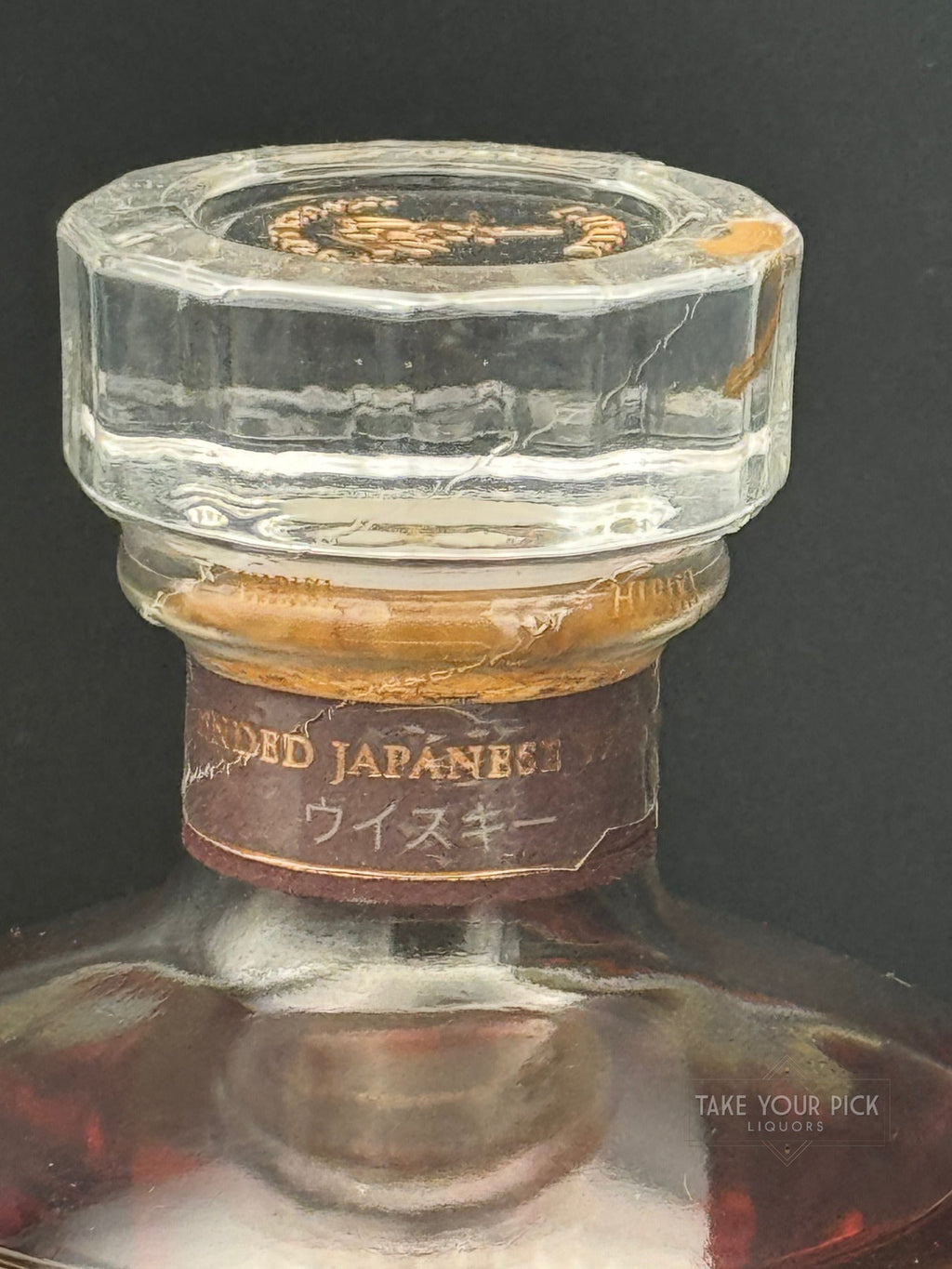 Vintage Japanese whisky bottle neck with aged label and glass stopper, showcasing premium liquor details.